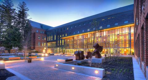 Paul College courtyard in the evening with interior lights aglow 