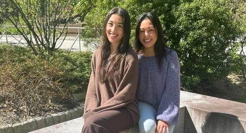 Leni and Michelle Lemos sit outside the Peter. T Paul College of Business and Economics