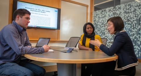 Associate Professor Emily Xu reviewing an article with accounting students