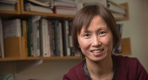 Shuili Du close up with bookshelves behind her