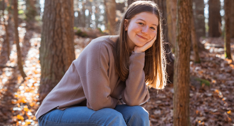 Chloe Villemure rests her chin on her hand and smiles at the camera