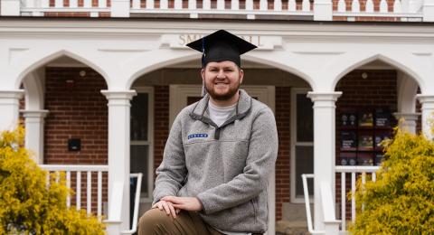 Zack Broder smiles at the camera while wearing a graduation cap.
