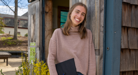 Zara Cheney leans against a shed, smiling