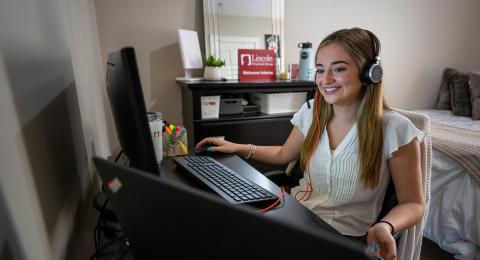 Claudia Fox sits at a desk looking at a computer screen in her Durham apartment.