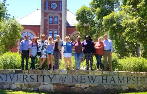 Daniel Silverman and residents of Lydia's House of Hope pose on the UNH wall on the Thompson Hall lawn