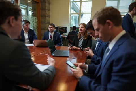 Members of Atkins Investment Group gather around a table to discuss work in Paul College's Bloomberg Terminal room.