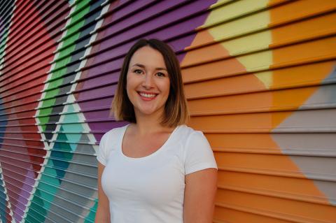 Kate Aiken, past Holloway participant standing in front of colorful wall