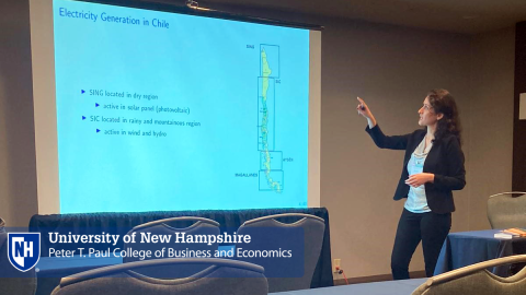 PHD Student pointing to screen presenting at conference.