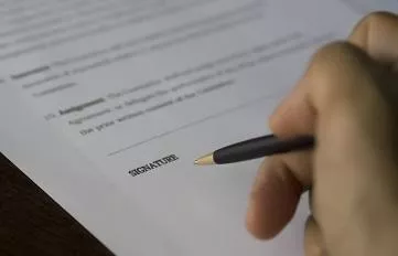 pen poised over contract to sign