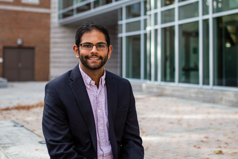 Ajaypal Panesar '21 A male student smiles at the camera while seated in Paul College's outdoor courtyard.