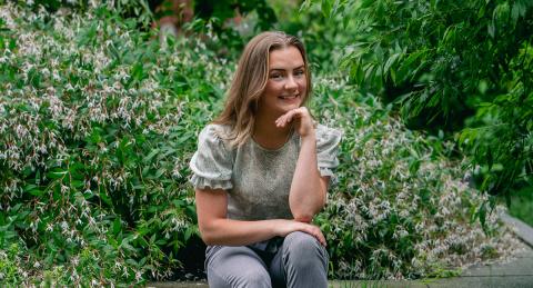 Clara Richards sits among the gardens outside Paul College.